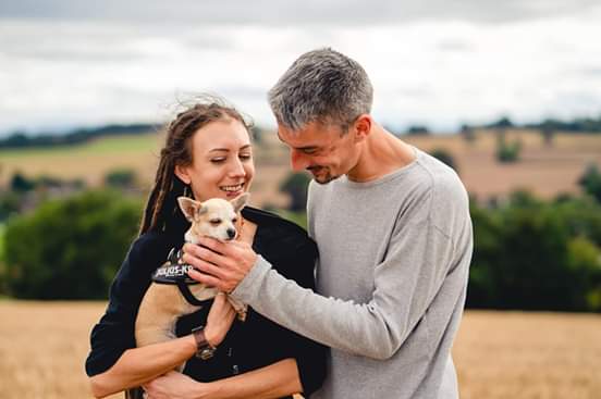 a man and woman holding a dog in a field