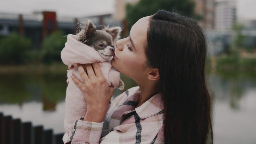 a woman kissing a small dog