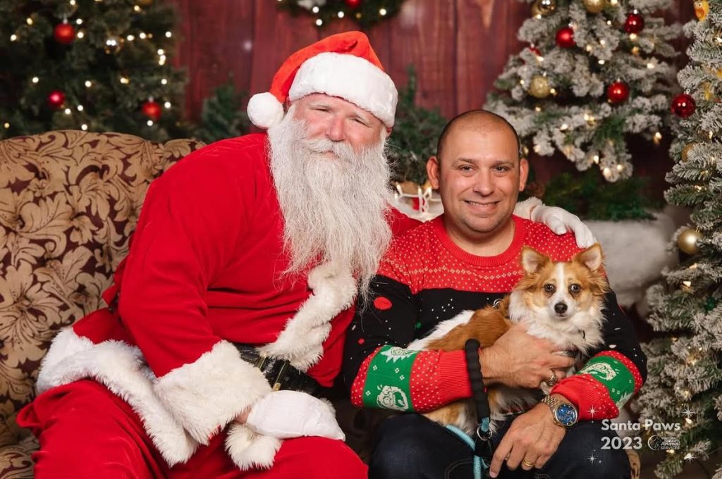 two men in santa suits and a dog