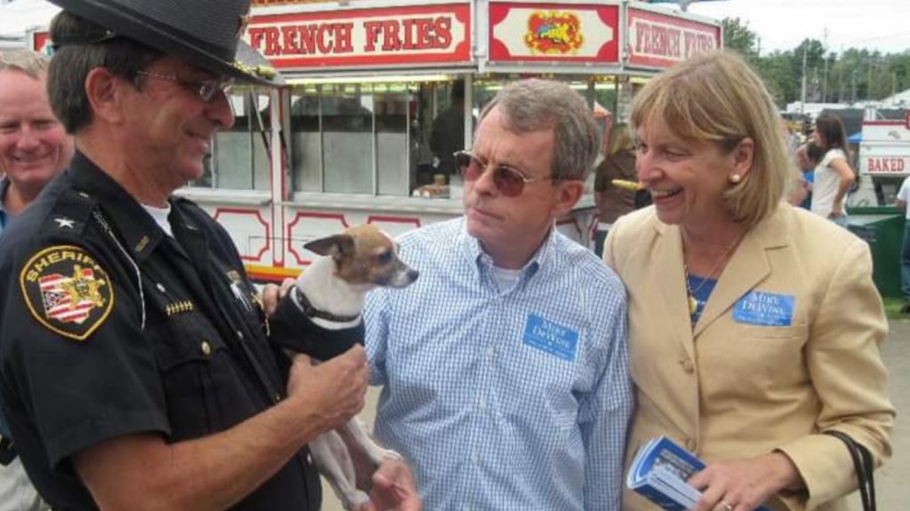 a man and woman holding a dog, midge the police Chihuahua